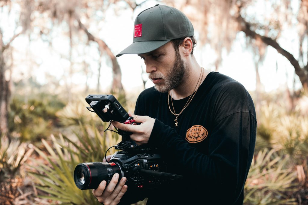 Man in woods filming.