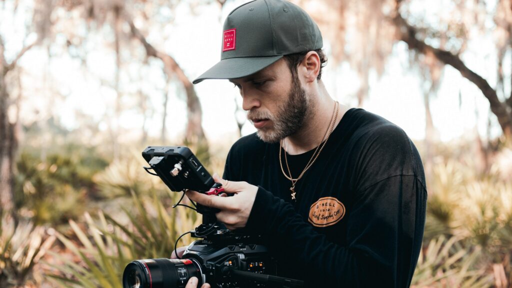 Man in woods filming.