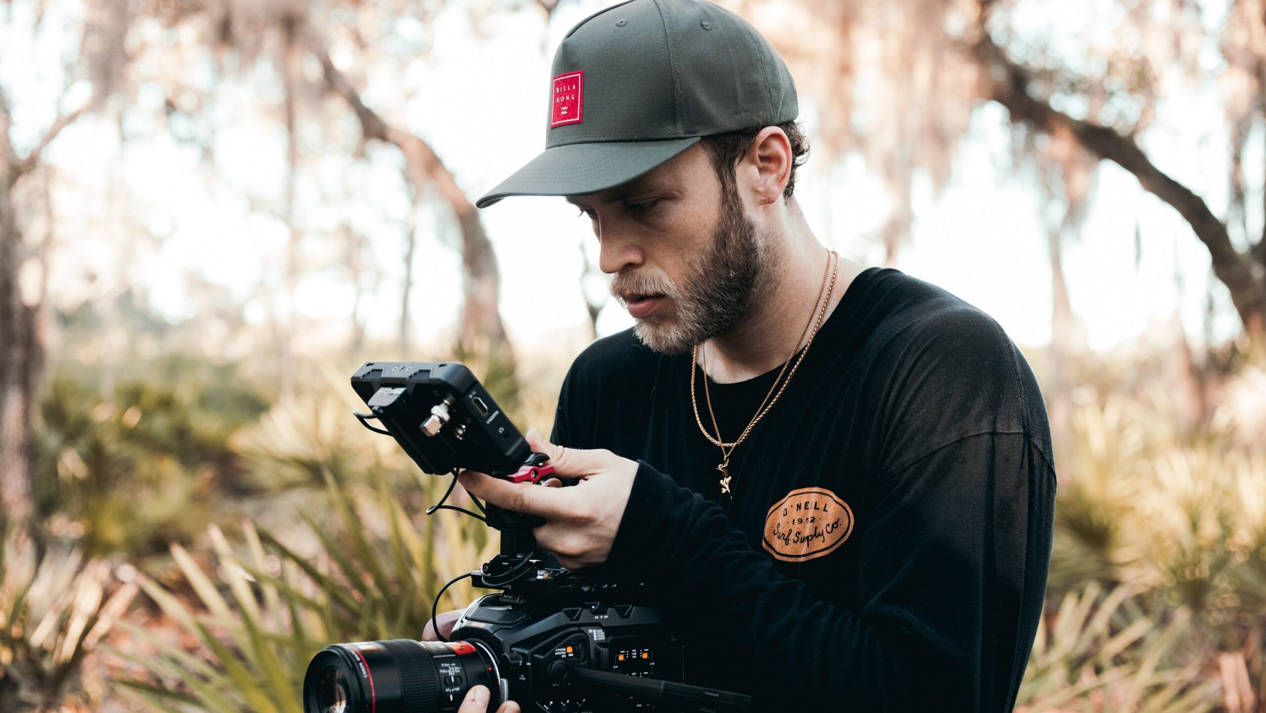 Man in woods filming.
