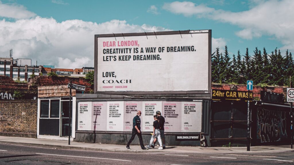 Coach brand billboard on street corner.