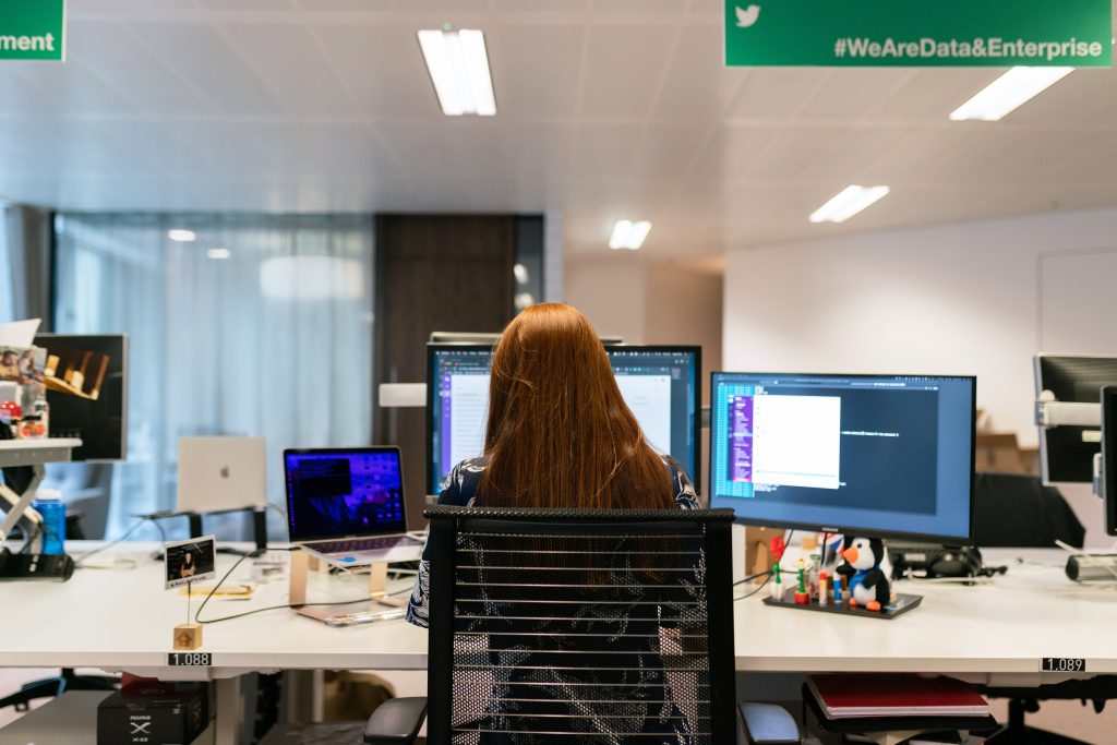 Woman sitting at desk with three monitors.