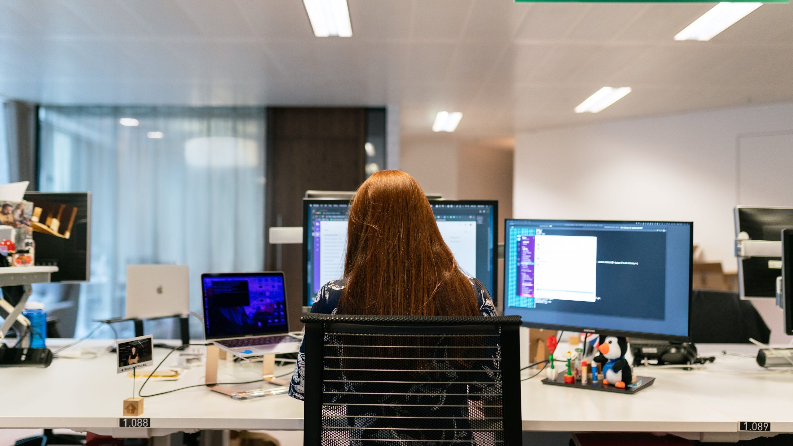 Woman sitting at desk with three monitors.
