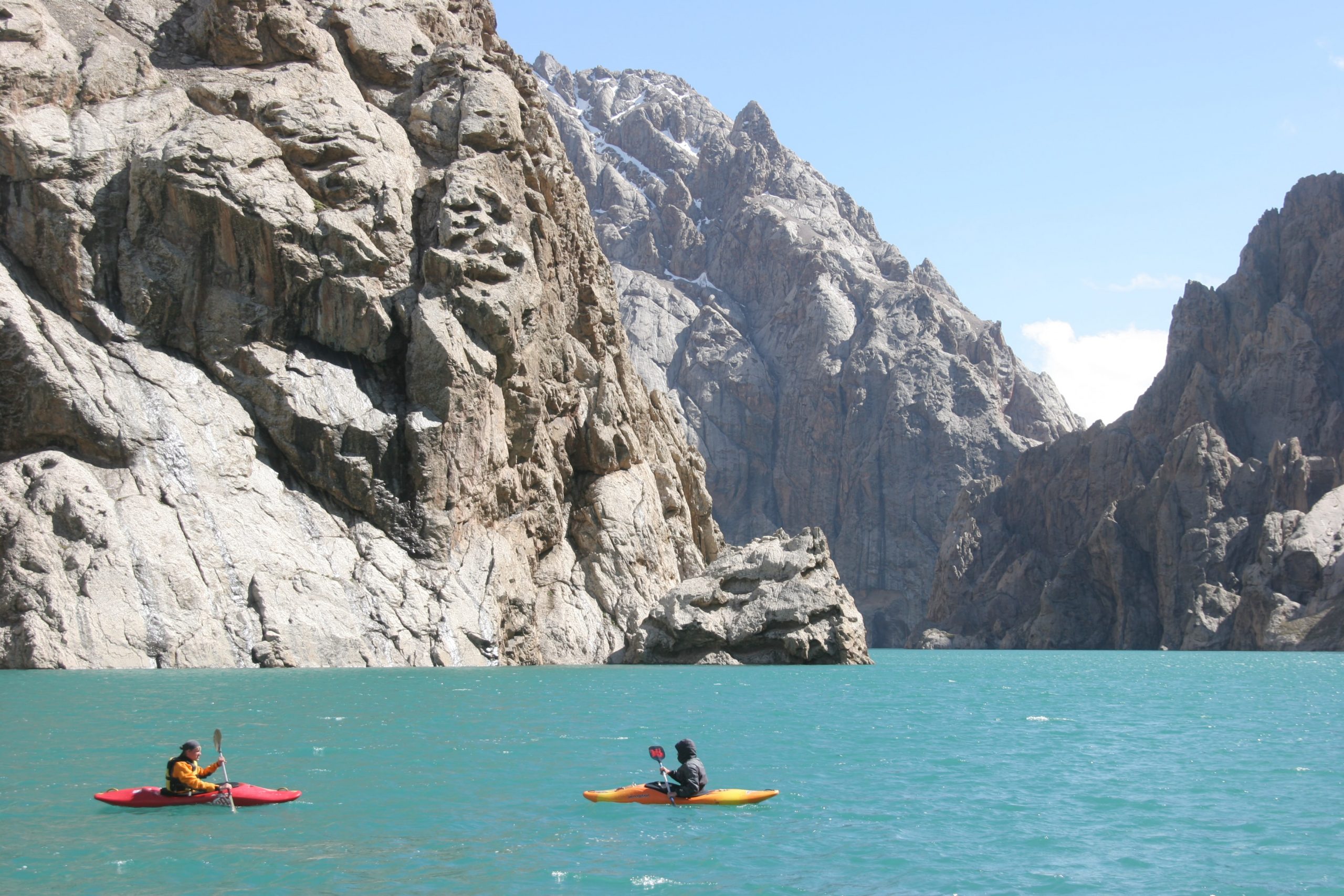 Kayakers on an alpine lake surrounded by rocky mountains.