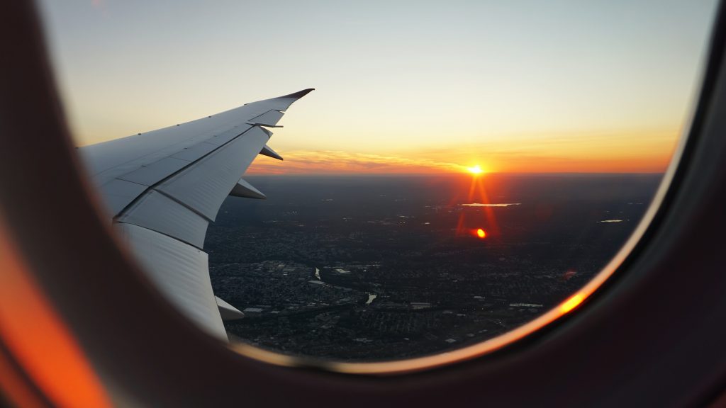 View of sunset and plane wing from plane window.