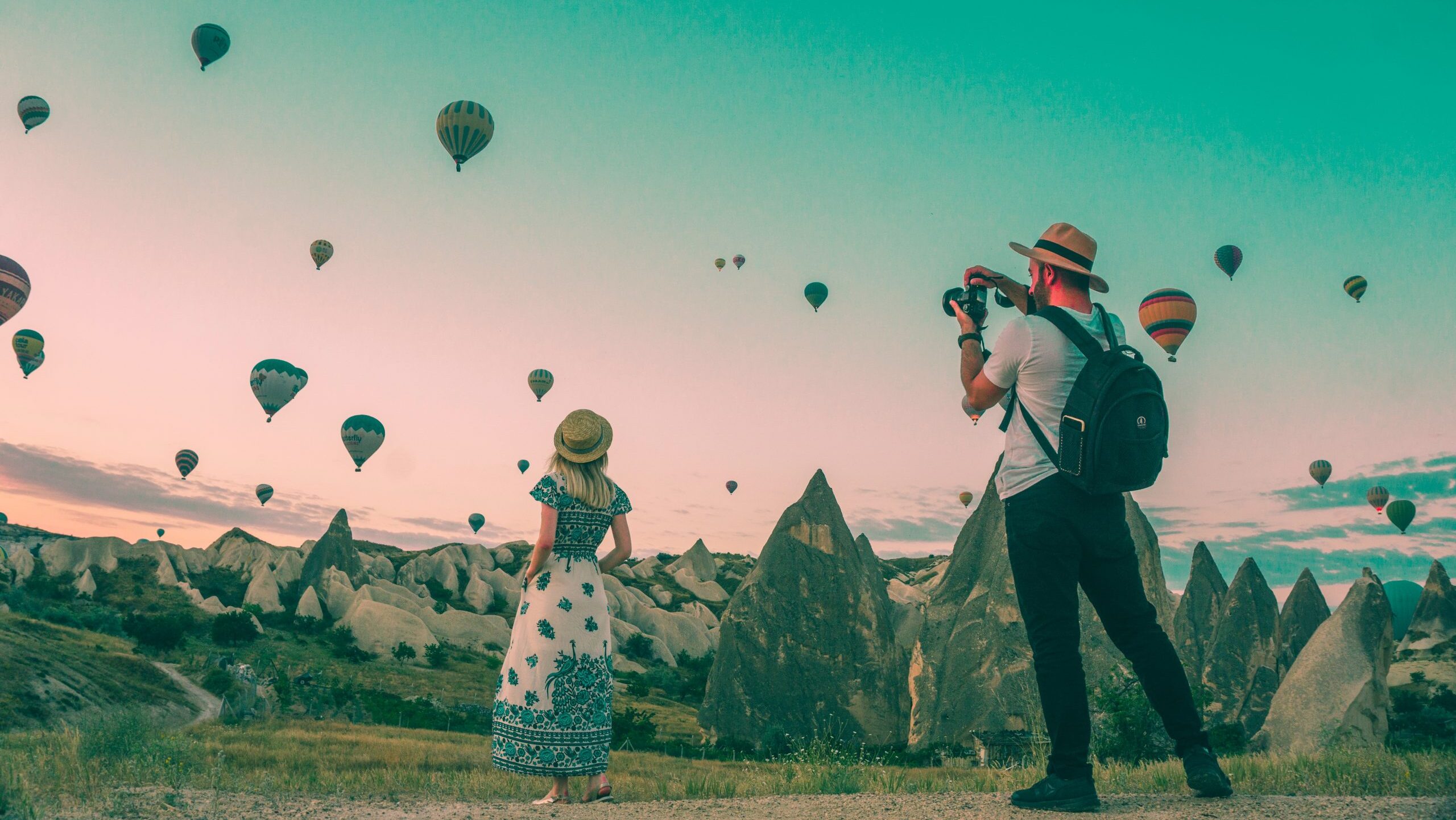 Woman being photographed in front of hundreds of hot air balloons.