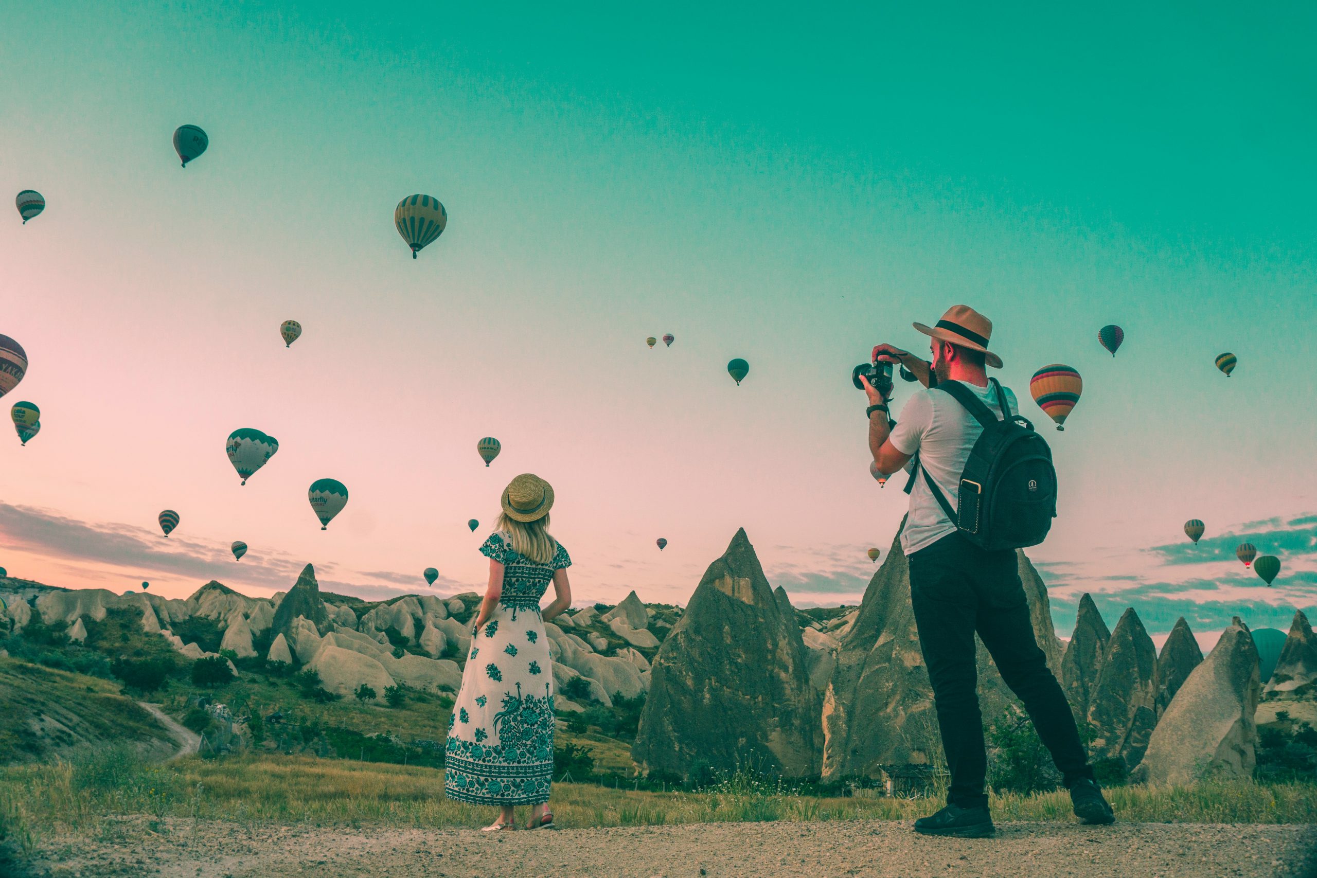 Woman being photographed in front of hundreds of hot air balloons.