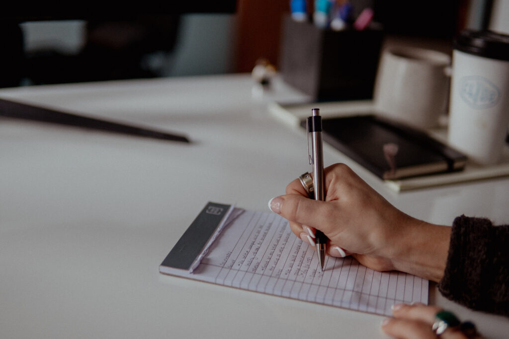Digital marketing intern writing on desk.